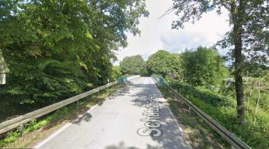 Das Bild zeigt die Schützenstraße, die die Bundesautobahn 1 von West nach Ost überquert. Die Hänge seitlich der Schützenstraße sind westlich und östlich der Bundesautobahn 1 mit Bäumen und Büschen begrünt.